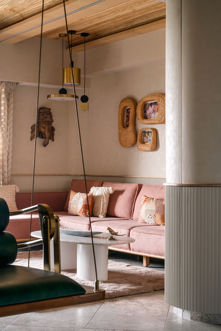 Dusty rose bouclé sofa, woven rattan picture frames, and a warm lime-plaster wall — colour that comes from material depth, not paint alone