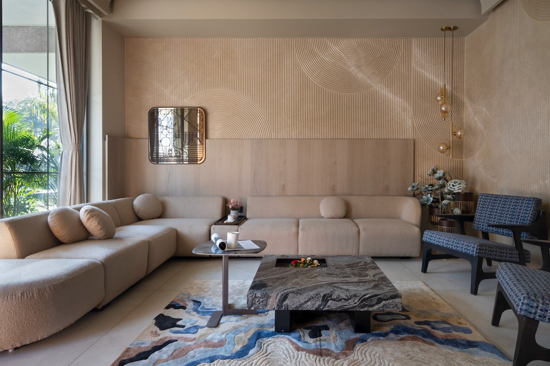 Sand-and-cream bouclé sofa, concentric arc relief feature wall in pale wood, Levanto marble coffee table, and hand-tufted abstract rug — warm minimalism at its richest